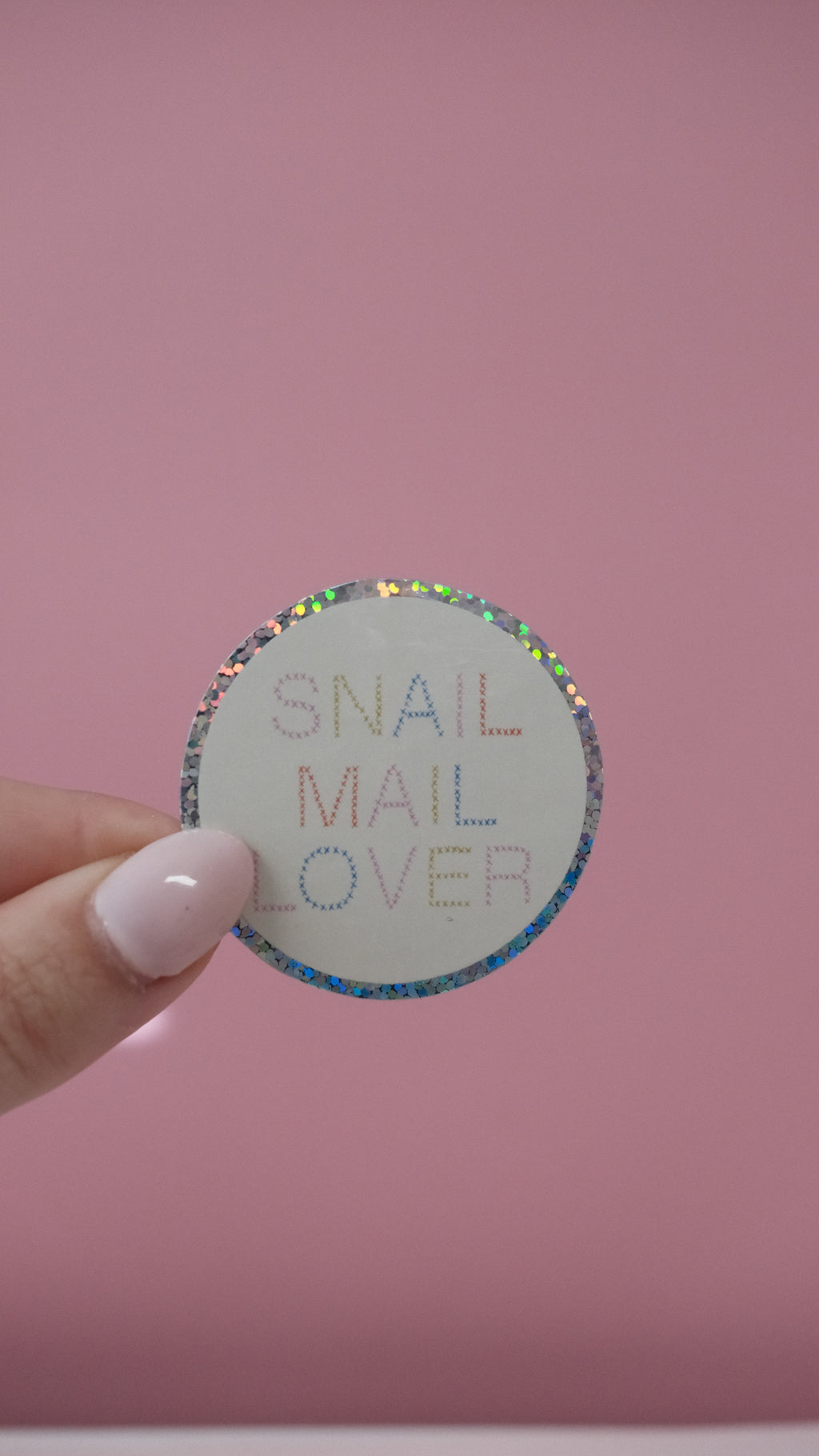 Sticker rond « SNAIL MAIL OVER » tenu par une main, bordure à pois