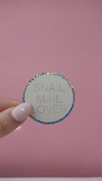 Sticker rond « SNAIL MAIL OVER » tenu par une main, bordure à pois