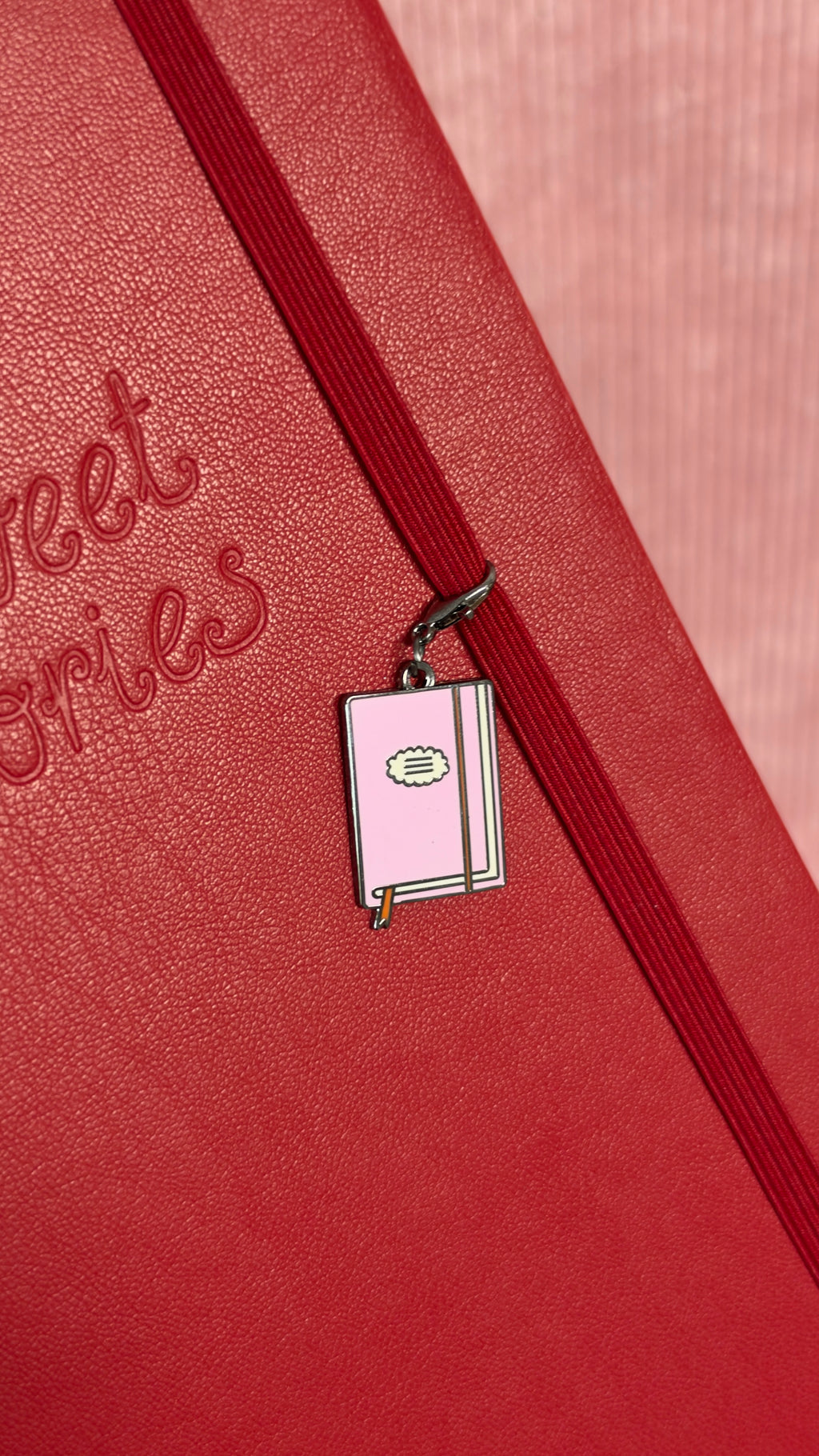Charm de carnet rose pâle accroché à l’élastique rouge d’un journal texturé pour la papeterie et le journaling par Nany Craft Shop
