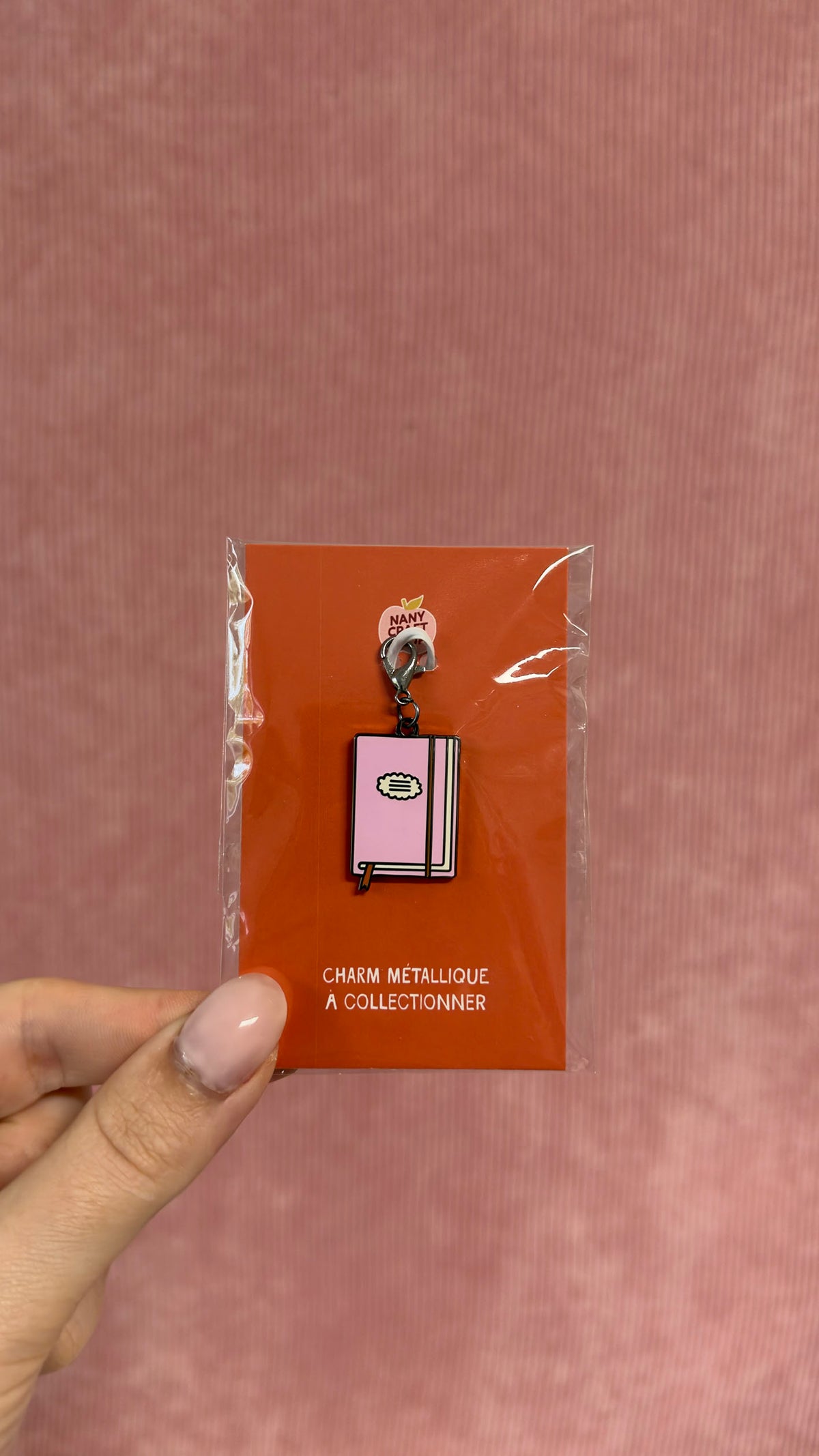 Charm métallique en forme de petit carnet rose présenté sur carte orange pour le journaling par Nany Craft Shop