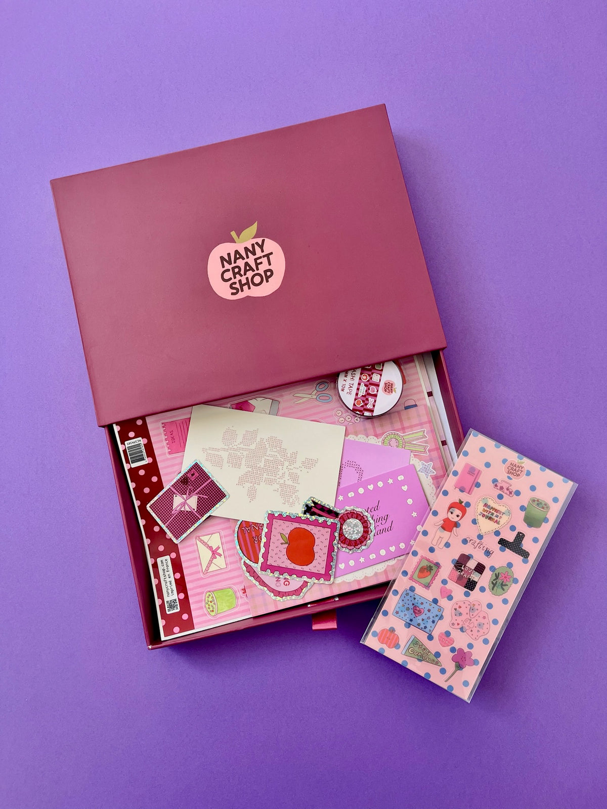 Coffret anniversaire avec boîte rose ouverte et feuilles de décoration